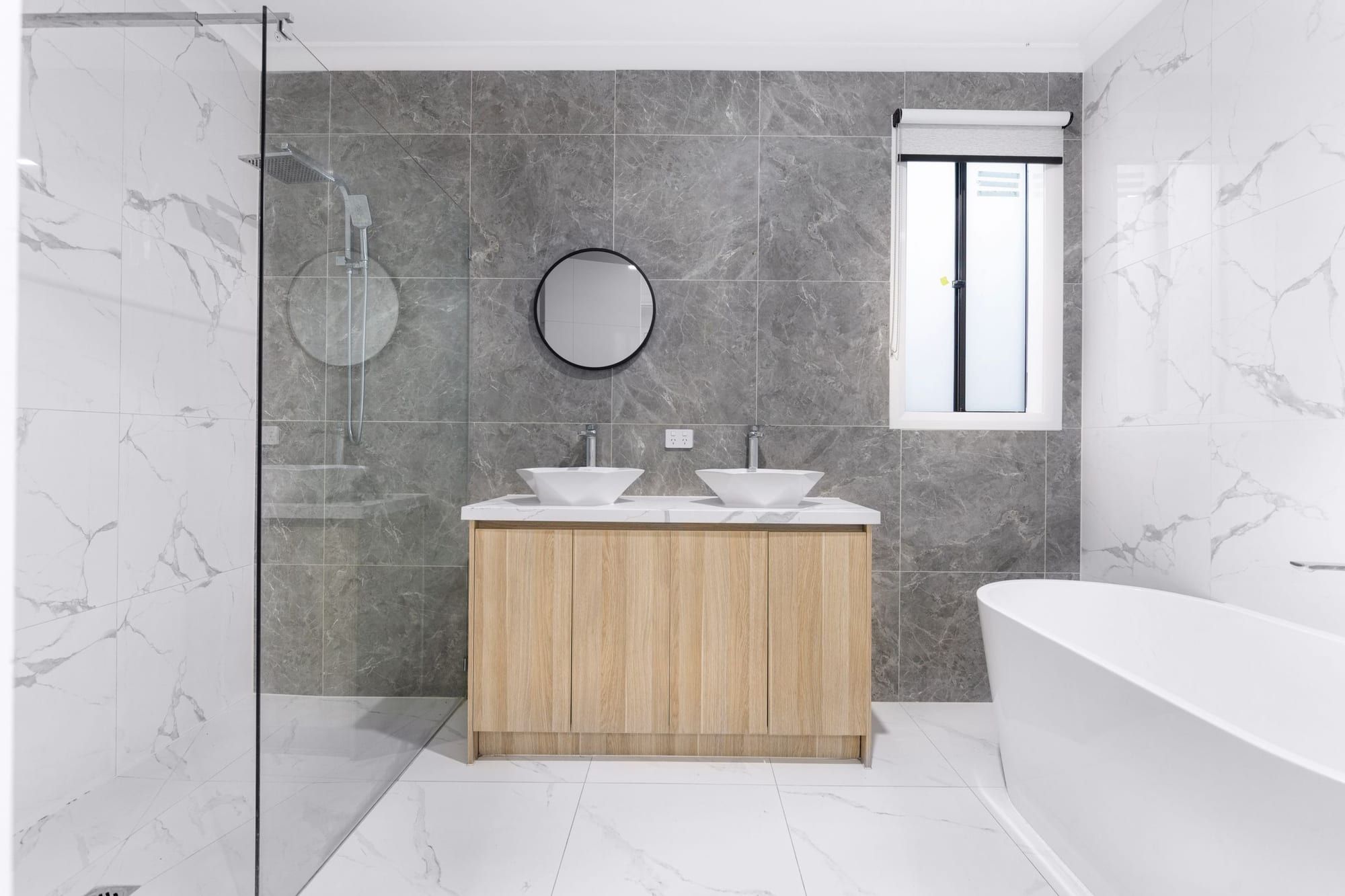 Bagno ristrutturato con pavimento in marmo chiaro, vasca a libera installazione, doccia a filo pavimento e mobile in rovere